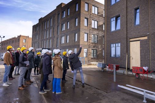 Een groep wordt rondgeleid door een nieuwbouwwijk waar circulaire materialen worden gebruikt.